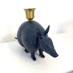 A glossy navy blue armadillo-shaped candle holder with a textured shell and a small gold cup on top, photographed on a white surface against a white background.