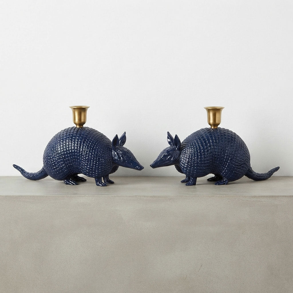 Two navy blue armadillo-shaped candle holders with gold candle cups, displayed on a light gray surface against a white background.